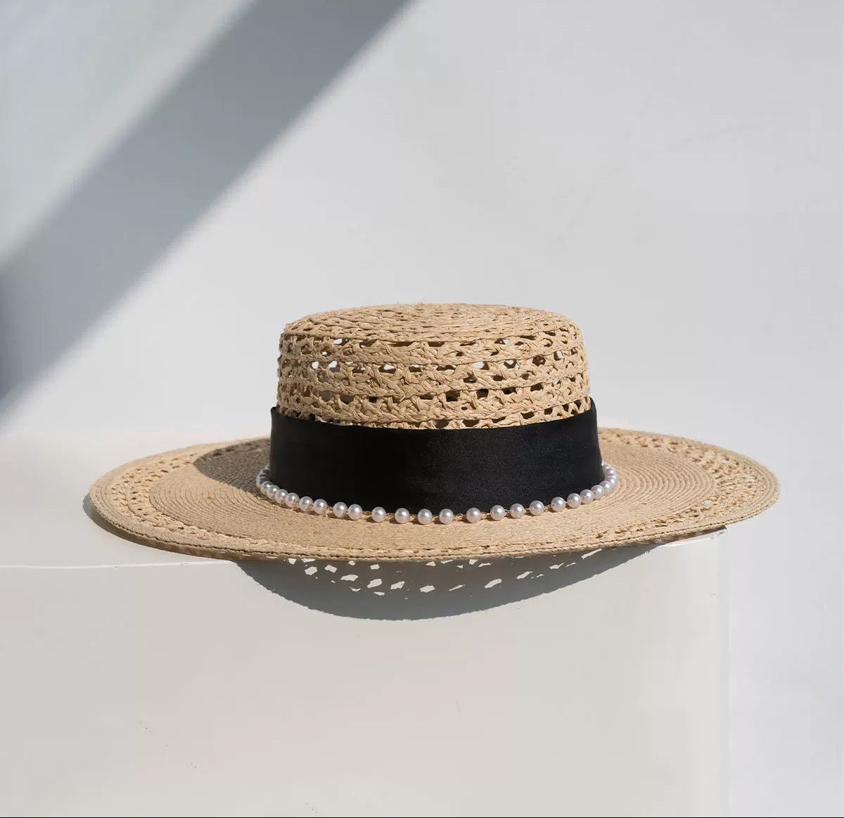 Woven straw hat with black band on a light gray background