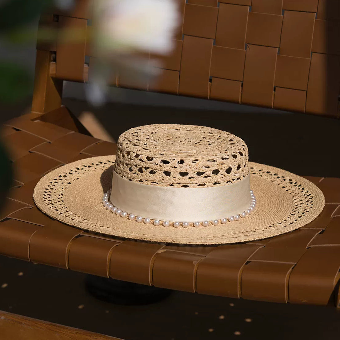 Woven straw hat with pearl band on a brown woven surface