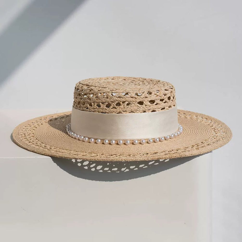 Beige straw hat with pearl band on a light gray background